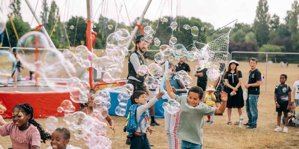 A group of children enjoy bursting a cloud of bubbles