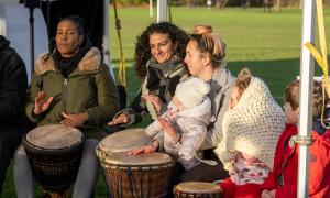A group of women sit playing African drums